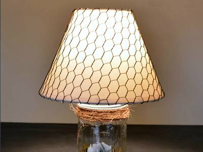 Chicken wire lamp is placed on the top of a bottle contained eggs.