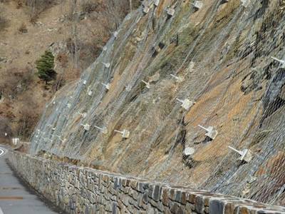 Rockfall barrier used as active stabilization system through its reinforcement anchors, bolts, and steel cables. 