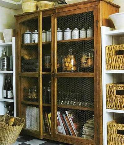 A chicken wire cupboard contains with many cookies, white cups and standing cups.