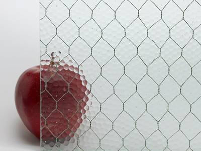 A red apple is placed behind a clear chicken wire mesh embedded glass.