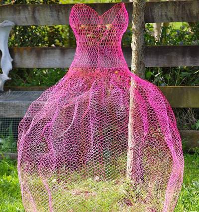 A chicken wire mesh made pink dress is place on the ground.