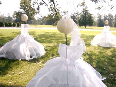 Three white dress coated human shape states are placed on the ground.