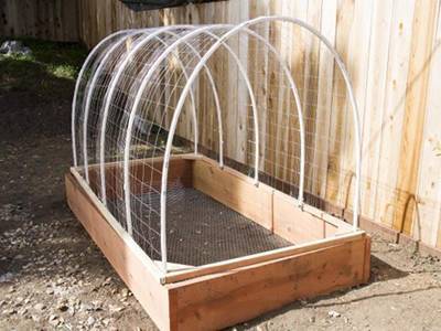A raised bed with arched cover on the top of the it.